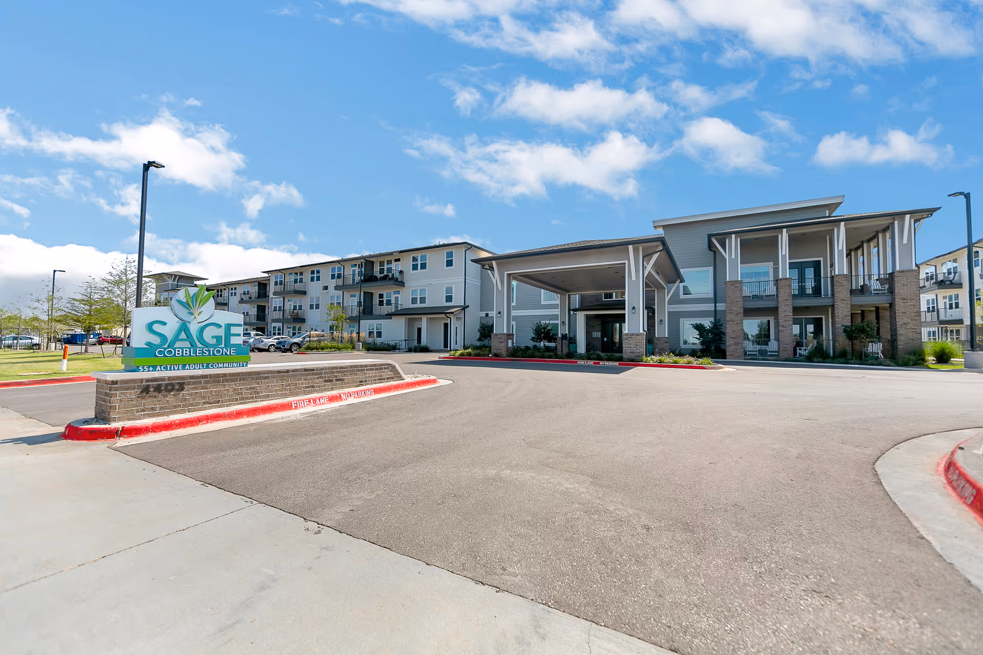 Exterior view of Sage Cobblestone Creek senior living facility with entrance and curved driveway.