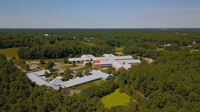 Aerial view of a large assisted living campus surrounded by trees.