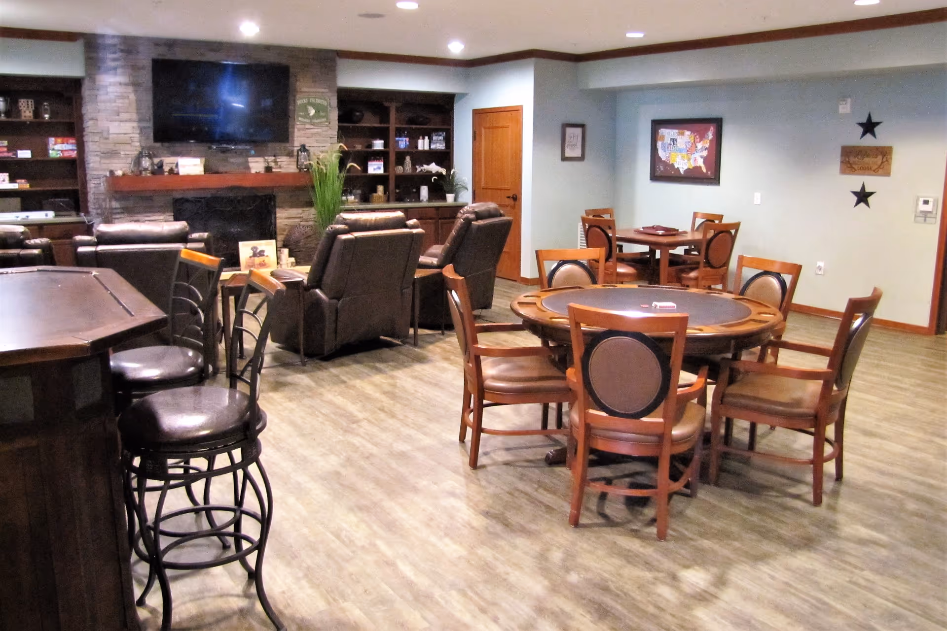 Martha's senior living common area with round tables, leather chairs, fireplace, and TV.