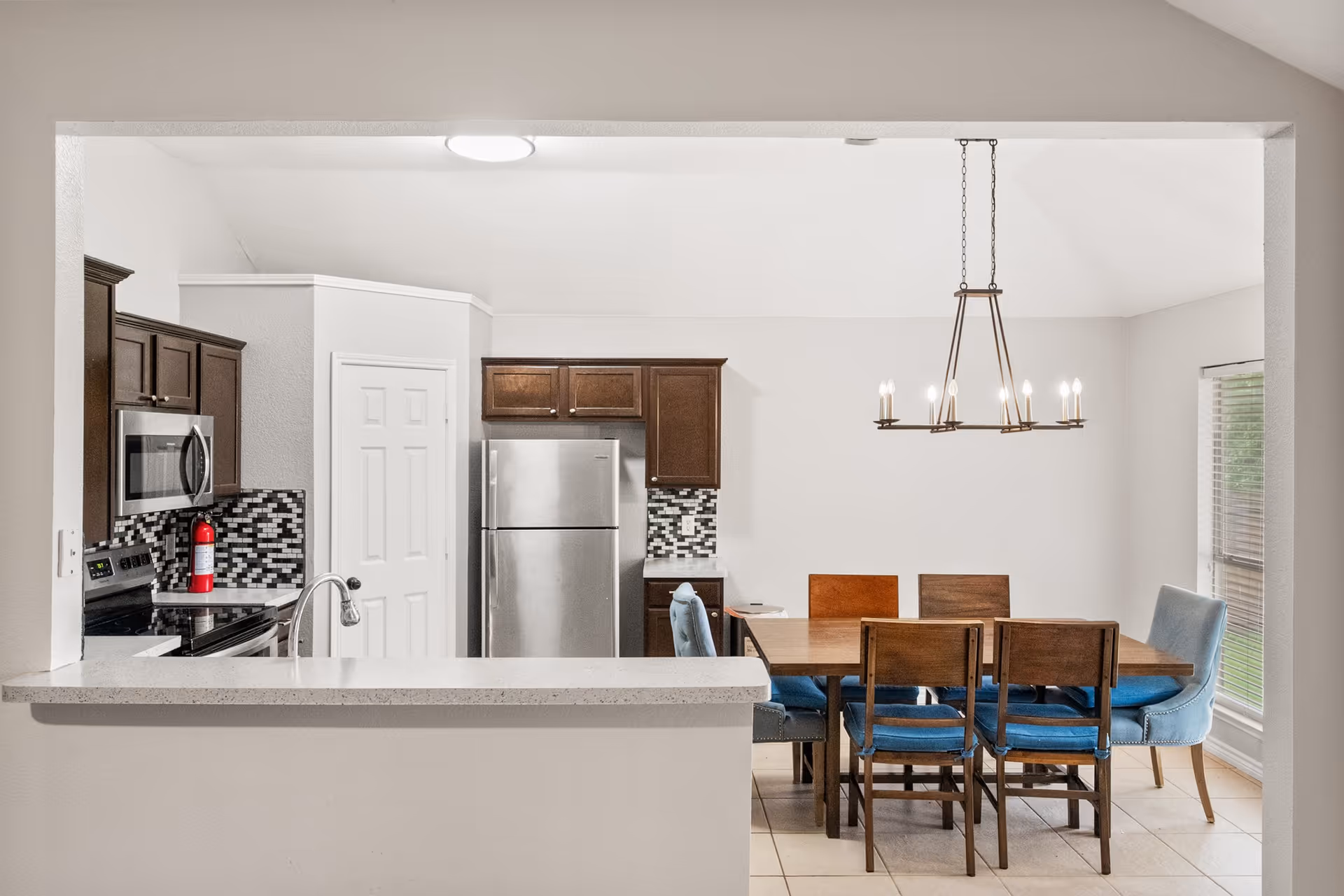Open kitchen and dining area with stainless appliances and a wooden table.