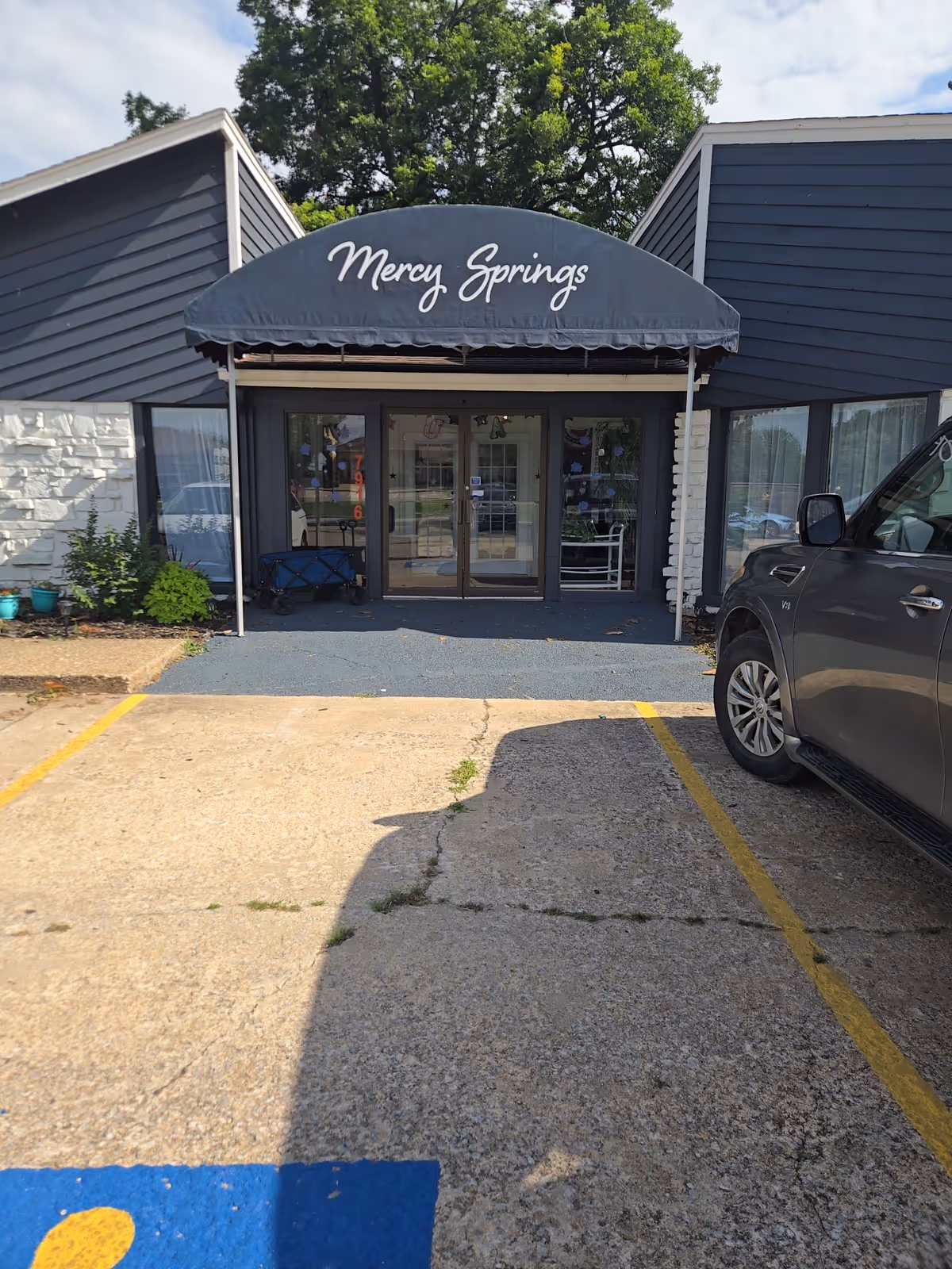 Mercy Springs Living Center entrance with a dark blue canopy over glass doors.