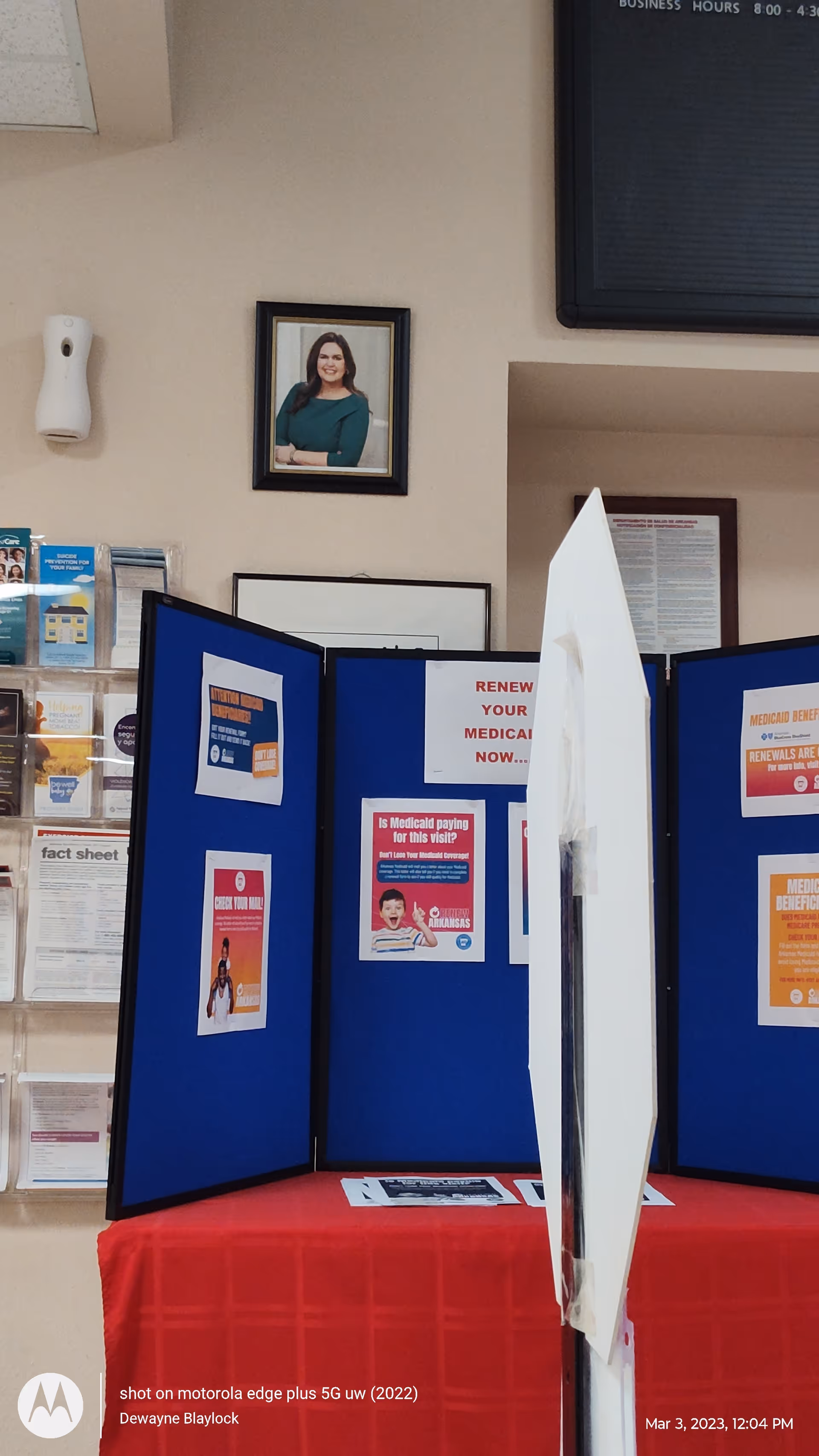 Interior display area with blue information boards, brochures, and a framed portrait on the wall.