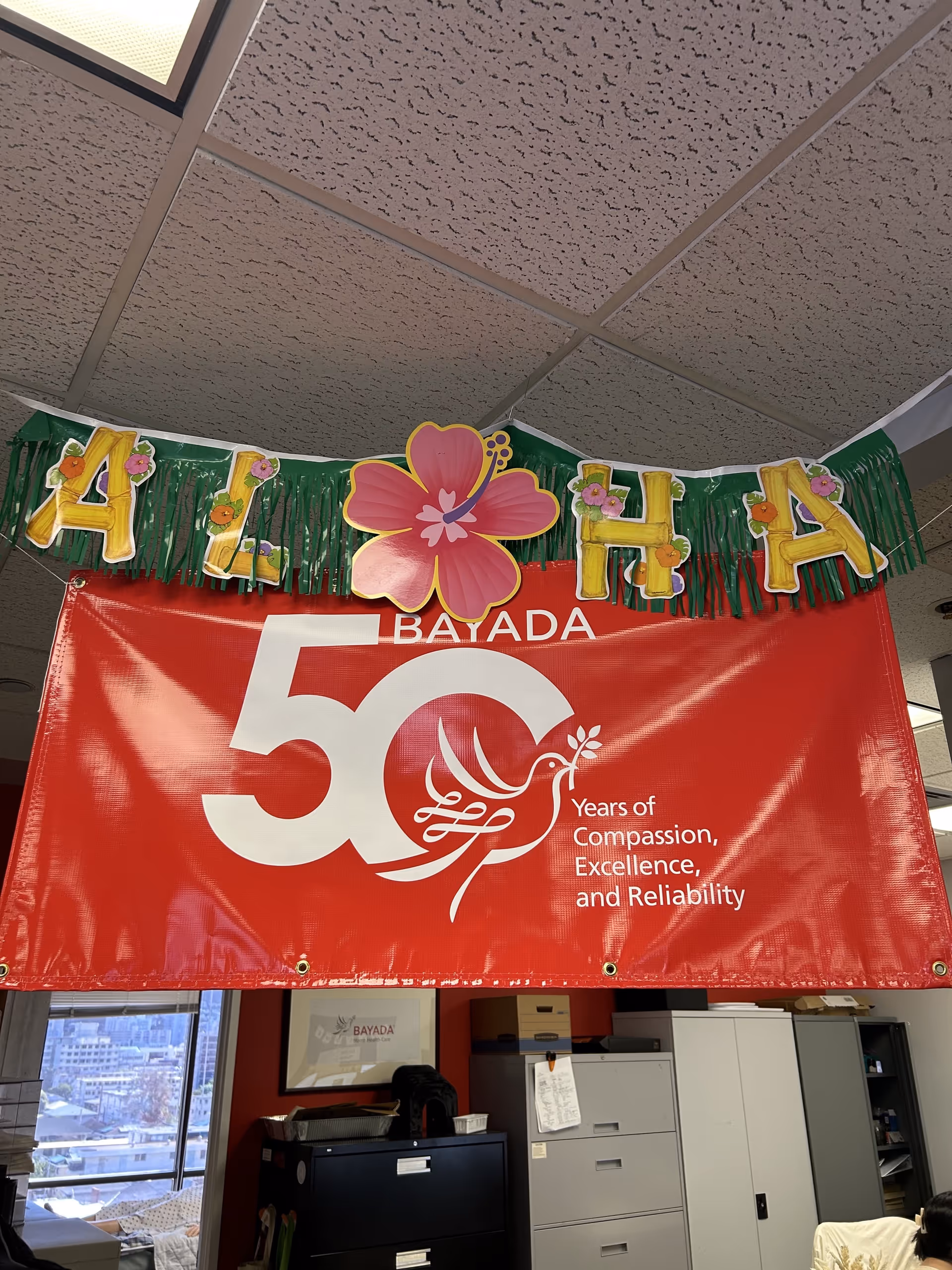 Interior office space with a large red BAYADA 50th anniversary banner and aloha garland.