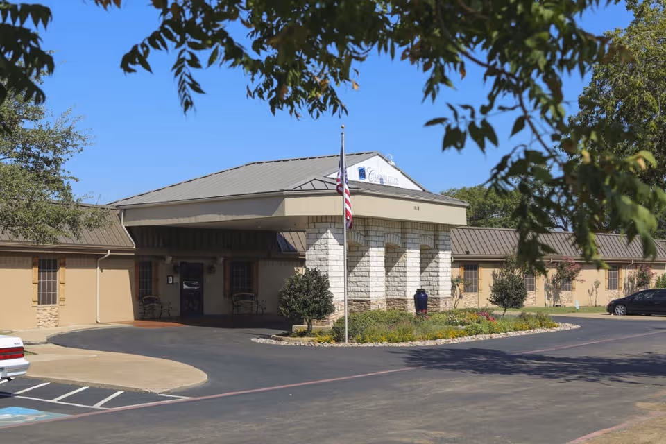 Front view of Carrollton Health & Rehabilitation Center entrance with flag and parking.