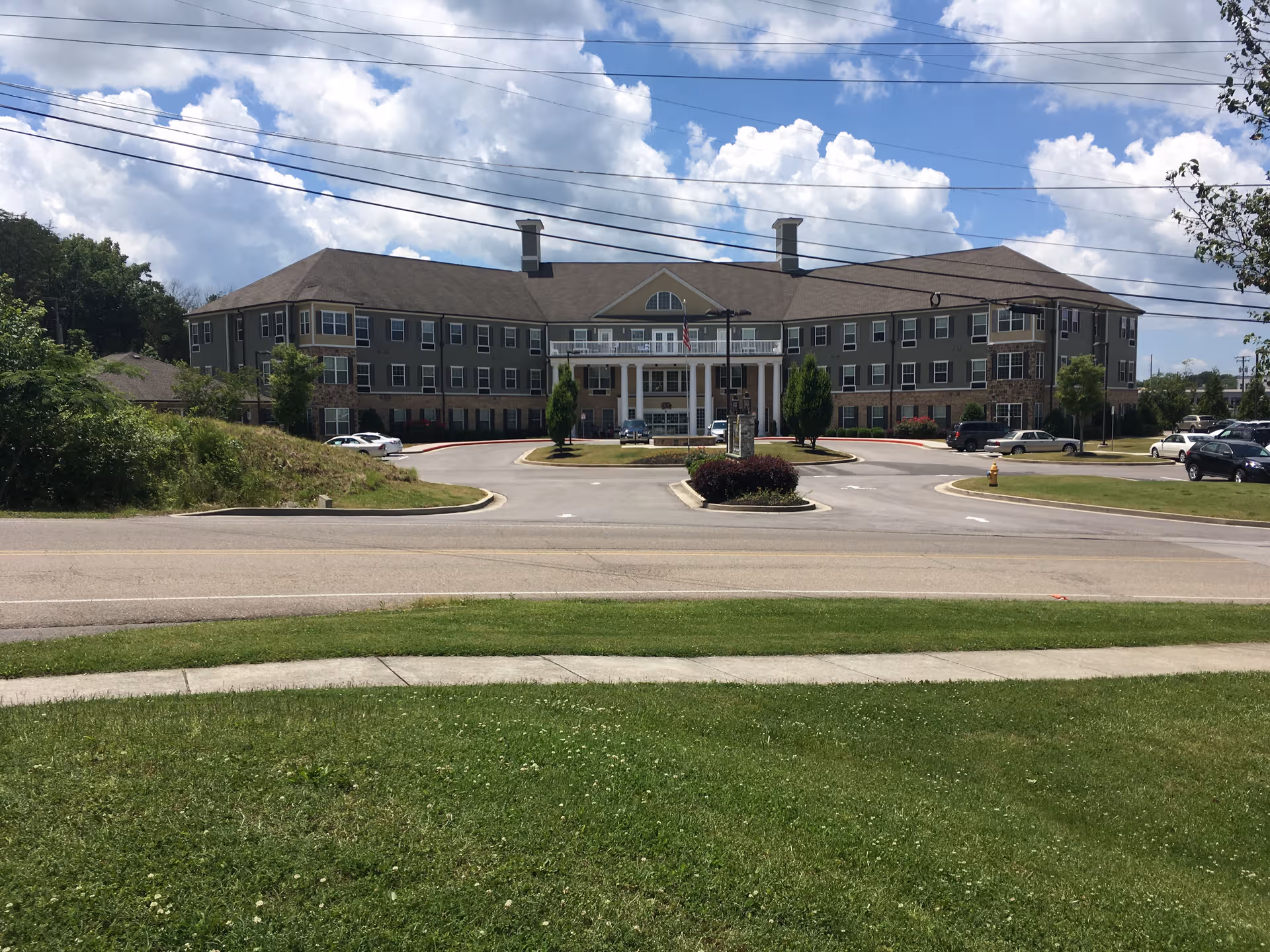 Large, modern senior living facility with a circular driveway and landscaped front entrance.