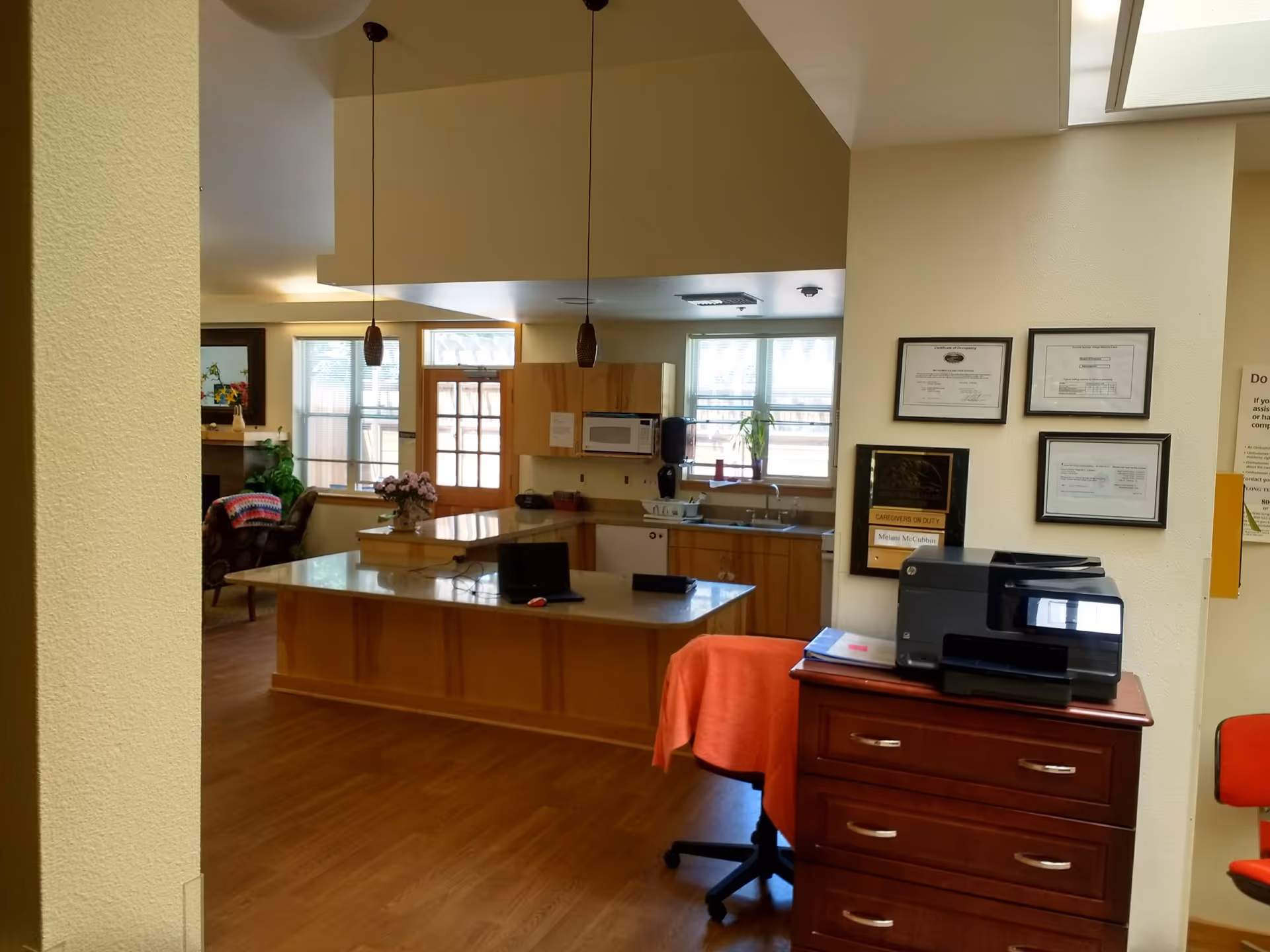 Kitchen area in a senior living facility with island, sink, and cabinets.