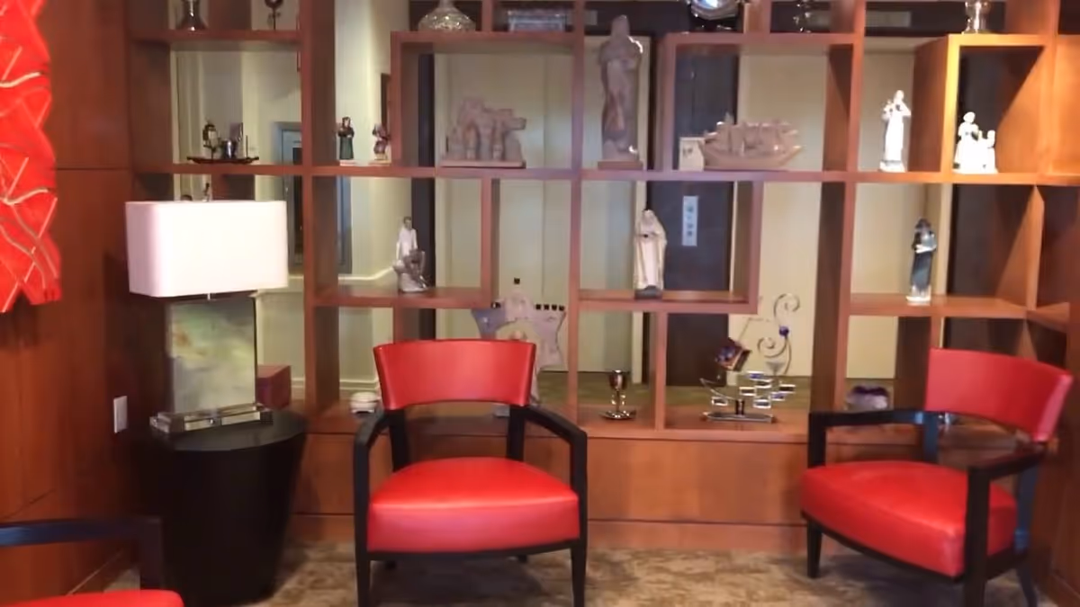 Interior lounge area with red chairs and open wooden shelves displaying figurines.