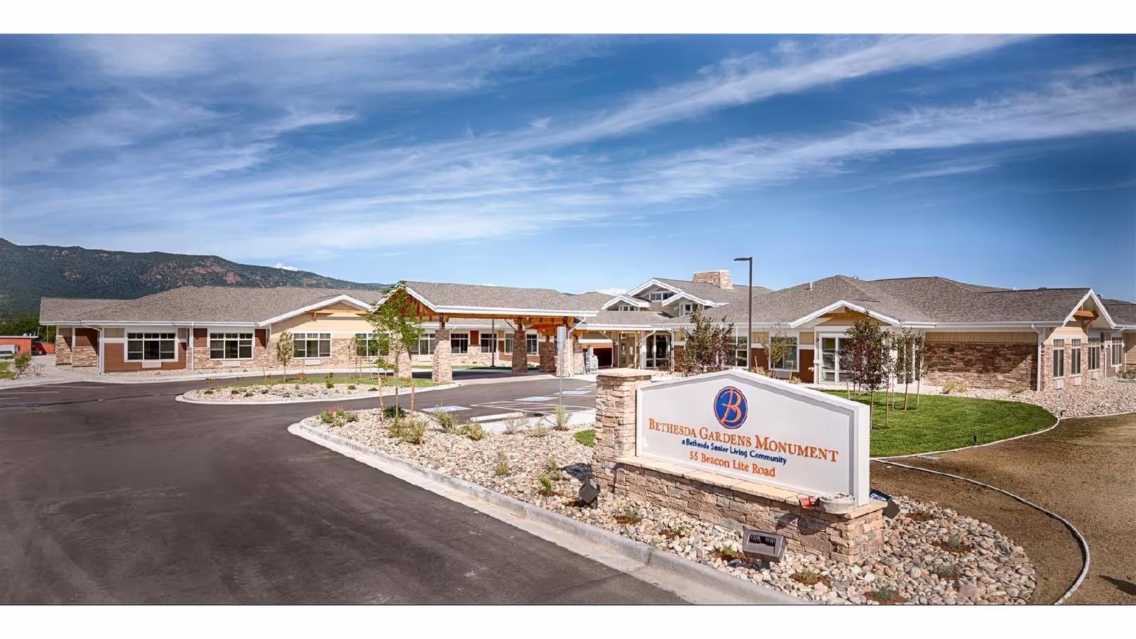 Exterior view of Bethesda Gardens Monument senior living center with sign and driveway