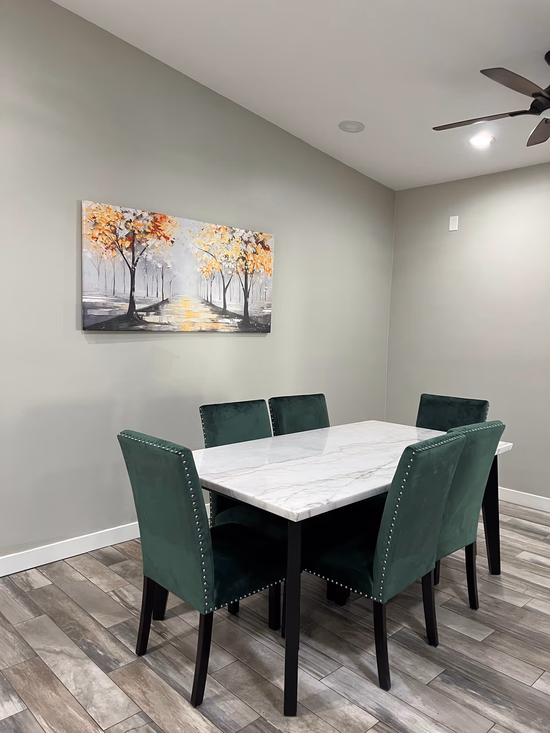 Modern dining area with a marble table and green upholstered chairs.
