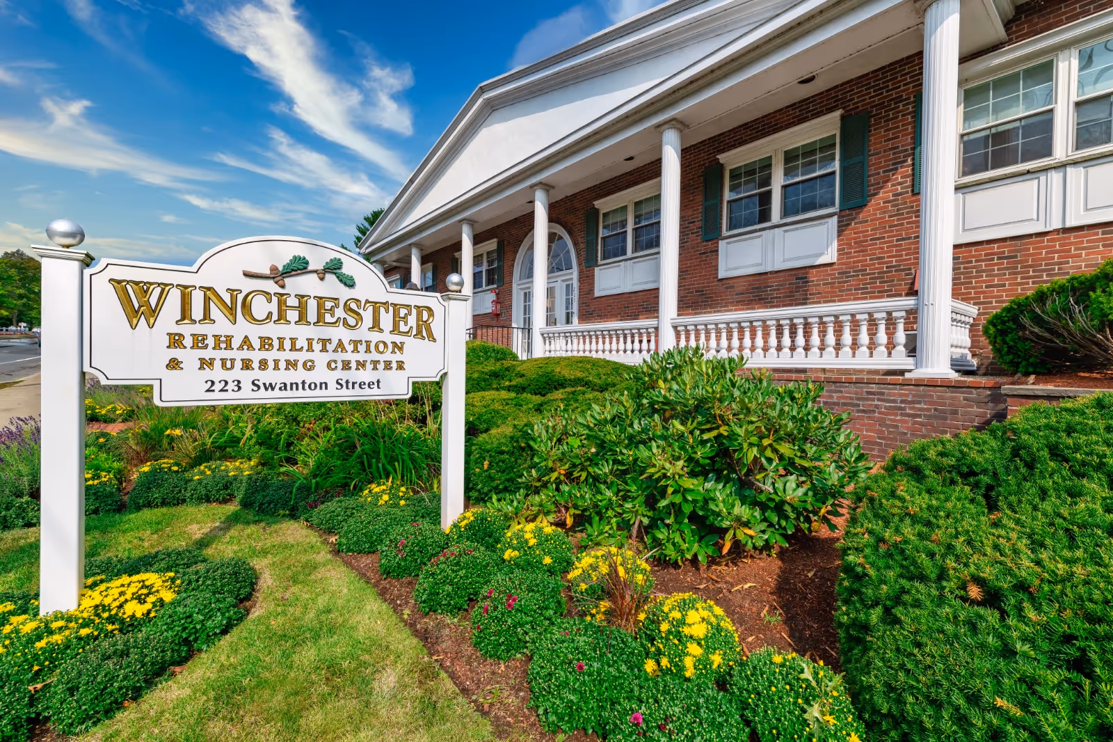 Exterior view of Winchester Rehabilitation and Nursing Center with sign and landscaped front yard.