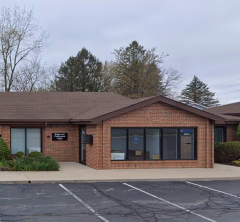 Brick, single-story building with large front windows and a parking lot.