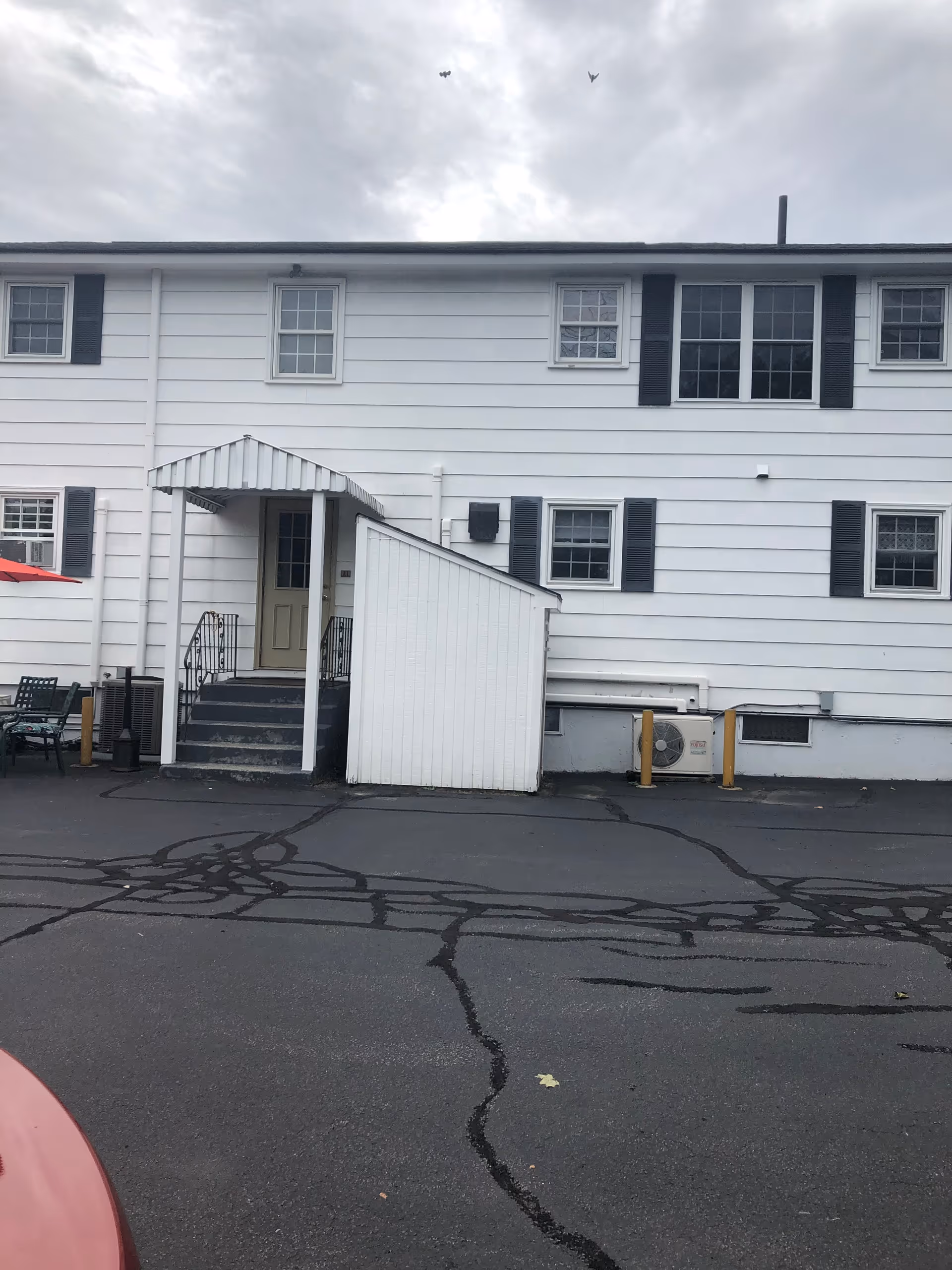 White two-story senior living facility exterior with entrance stairs and parking lot.