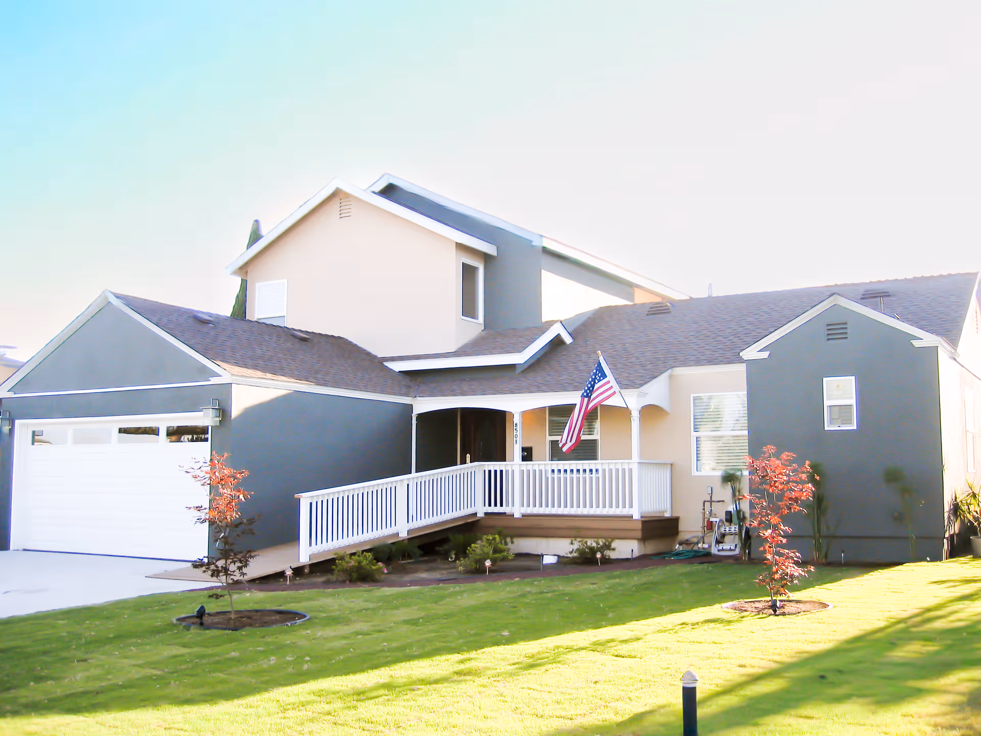 Americare Assisted Living exterior front view with porch, flag, and green lawn.