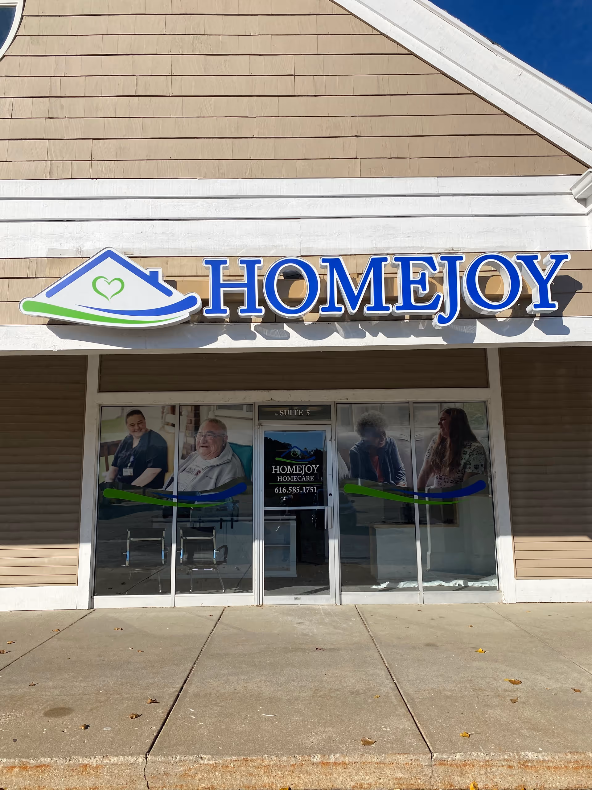 Exterior storefront of HomeJoy Corporate with a large blue sign and glass entrance doors