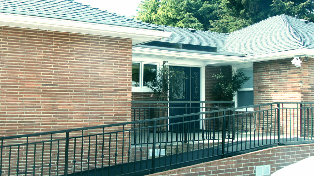 Exterior view of a brick senior living facility with a ramped entrance.