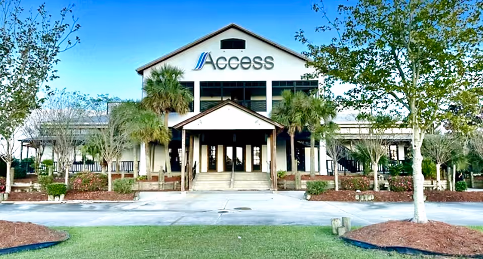 Front view of Access Home Care Solutions building with trees and glass entrance.