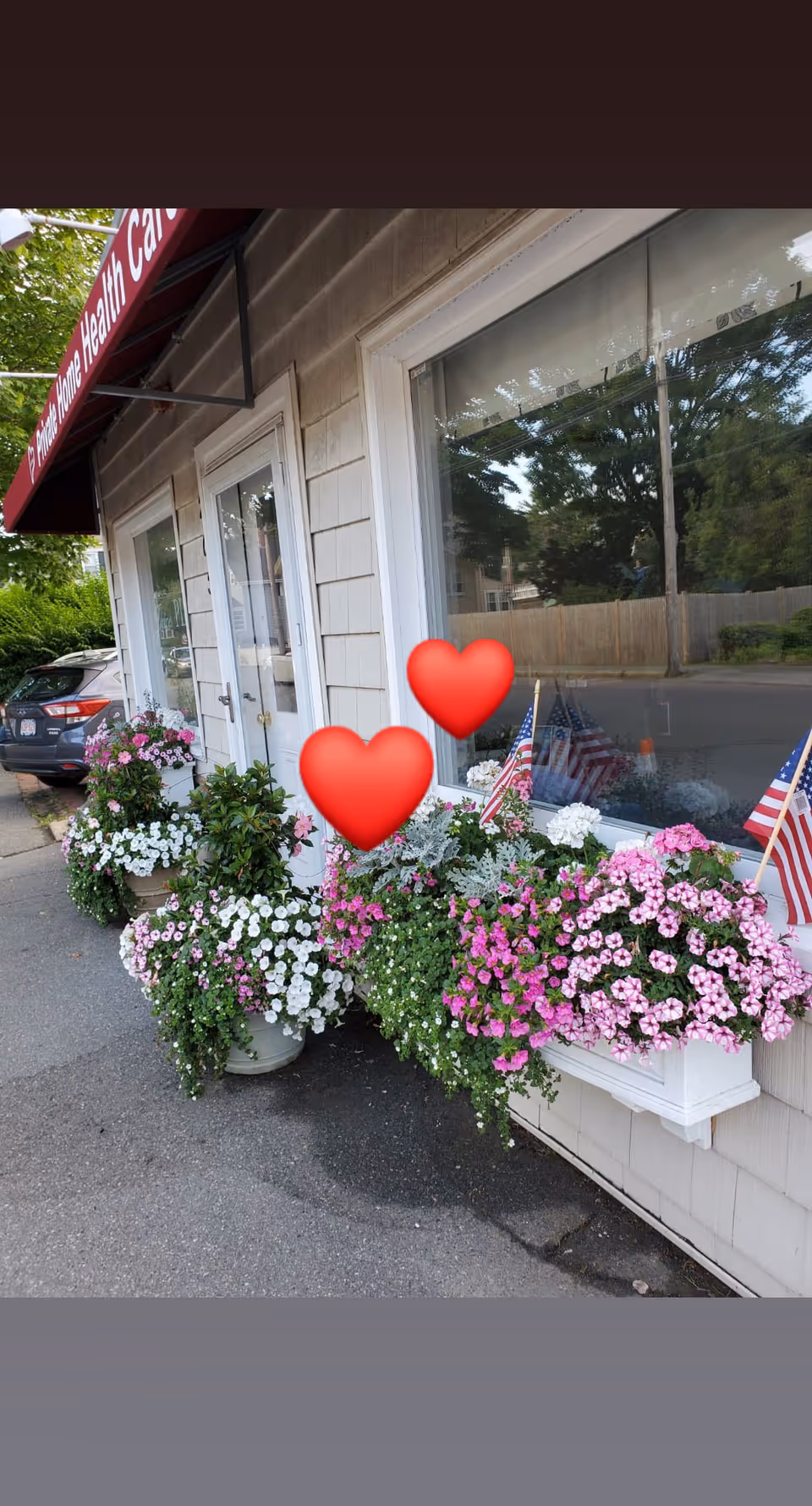 Exterior view of a facility storefront with colorful flower planters along the sidewalk.