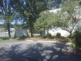 Exterior view of Retirement Center of Arkansas with sign, trees, and landscaping.