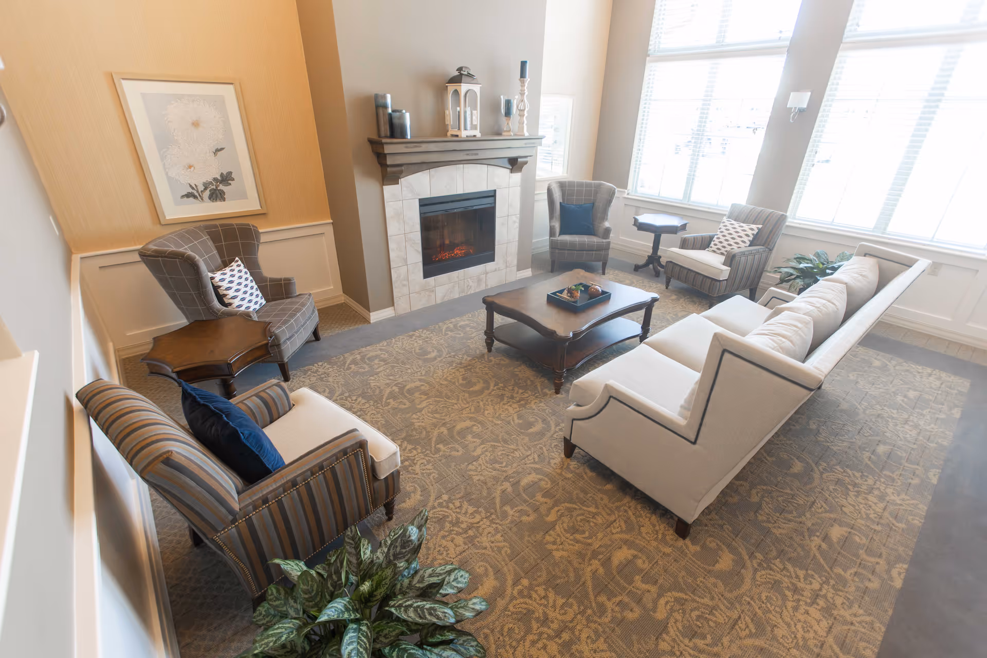 Bright living room with beige sofa, armchairs, coffee table, and a fireplace.