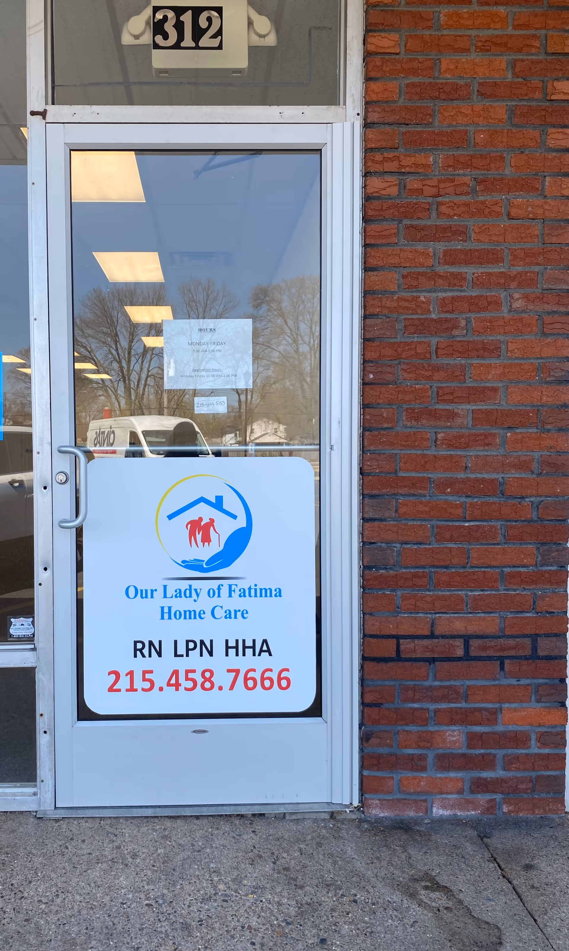 Front entrance of Our Lady of Fatima Home Care, brick exterior with glass door and sign.