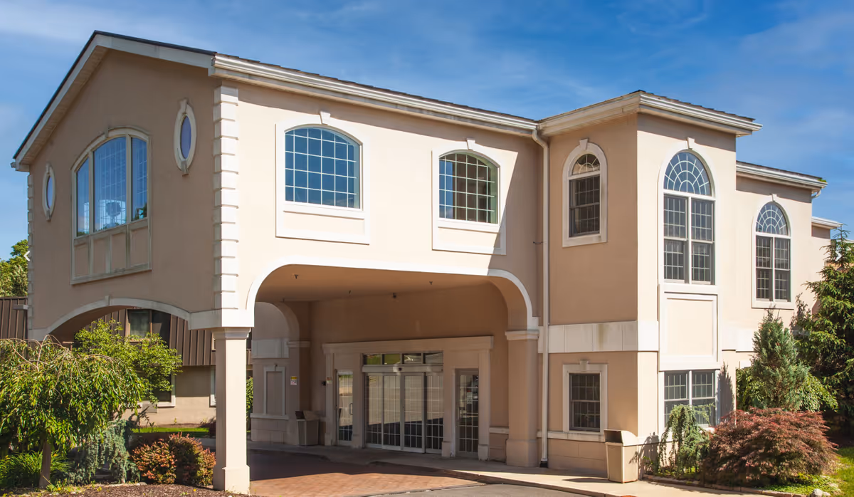 Beige two-story senior care center with arched windows and a covered entrance.