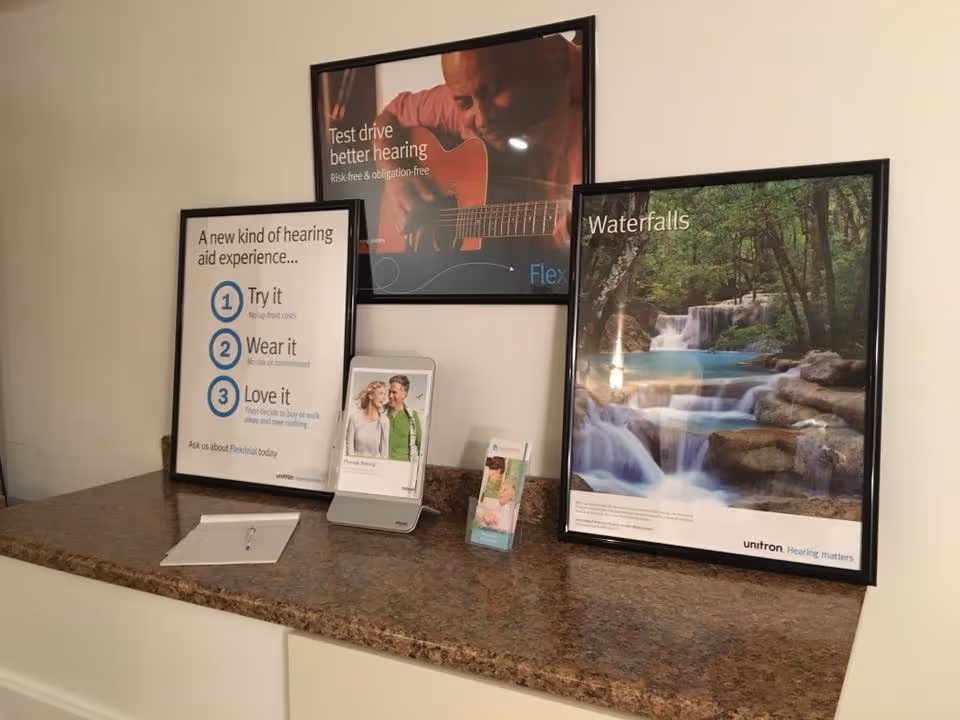 Hearing-aid posters displayed on a granite countertop in an interior hallway.