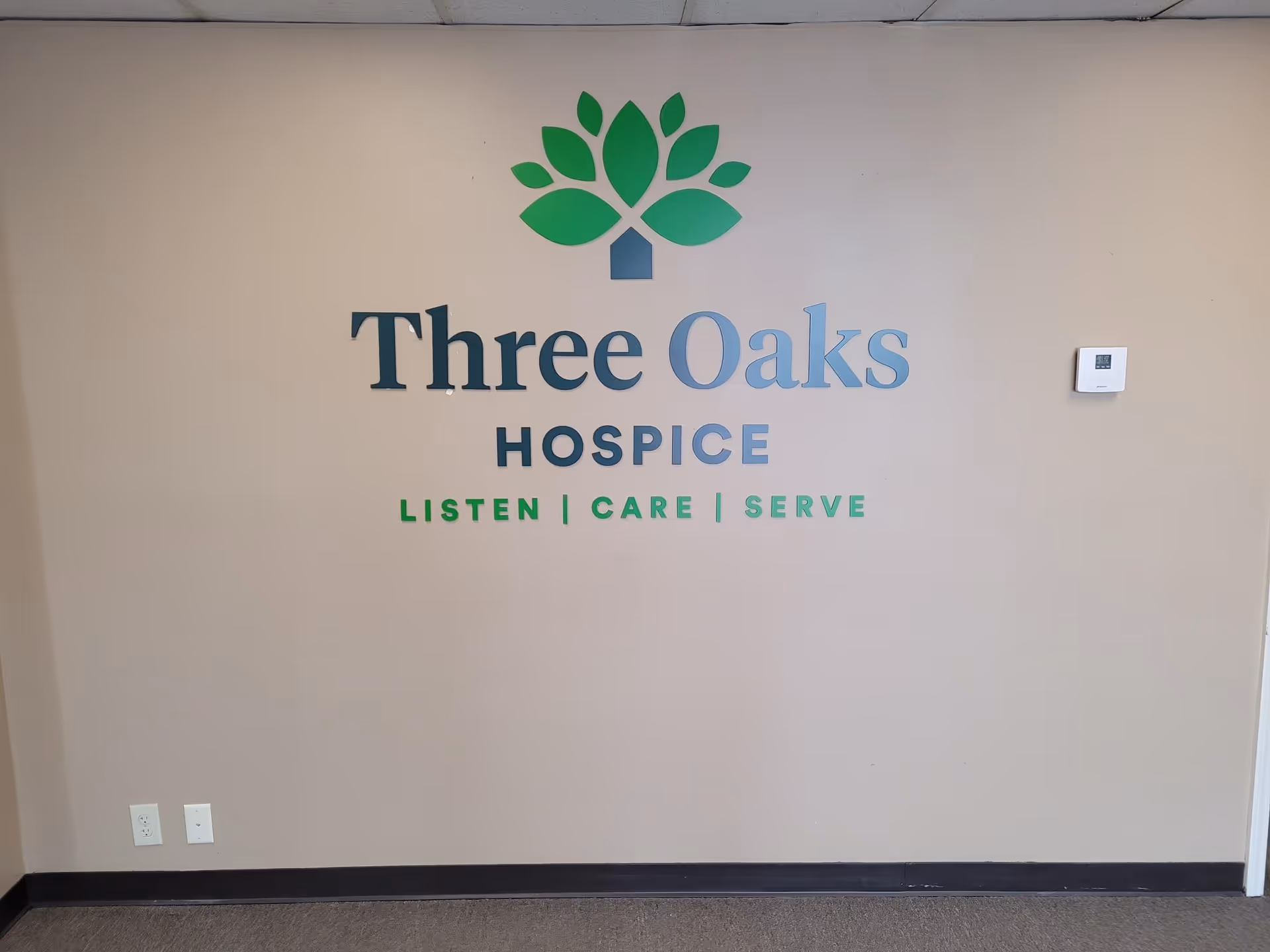 Interior wall displaying Three Oaks Hospice logo with green leaf graphic.