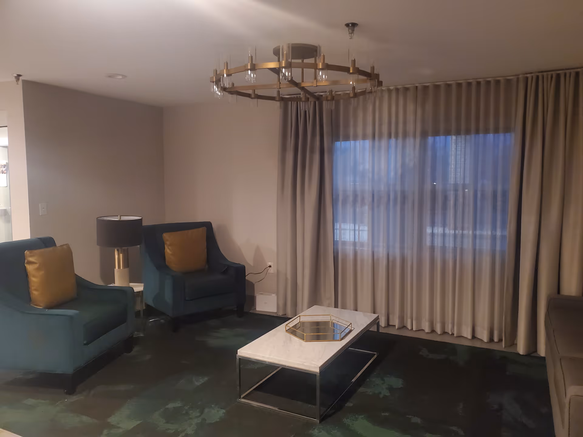 Avantara Elgin lounge with teal chairs, gold cushions, and a glass coffee table.
