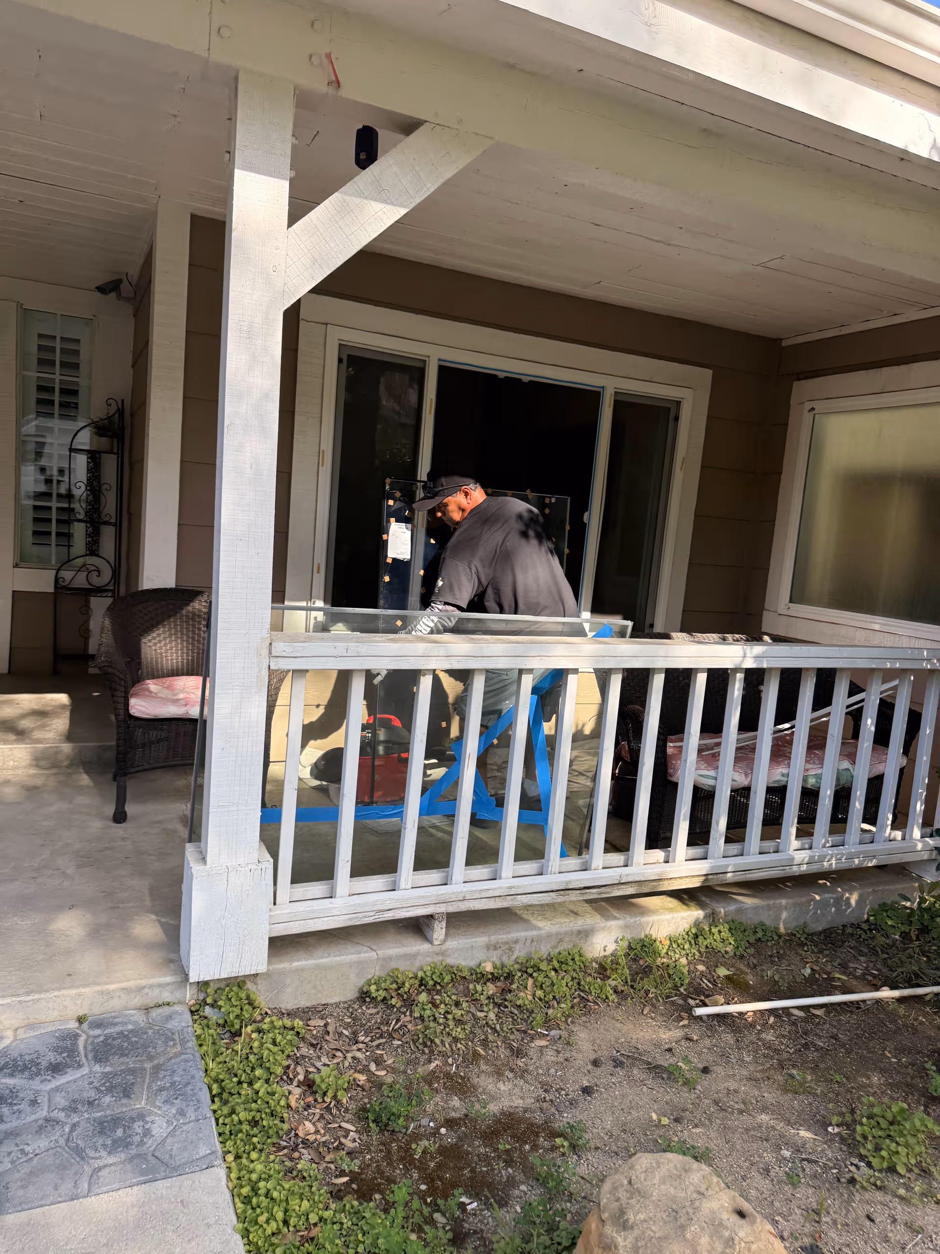 A man in dark clothing works on equipment on a porch outside a senior living home.