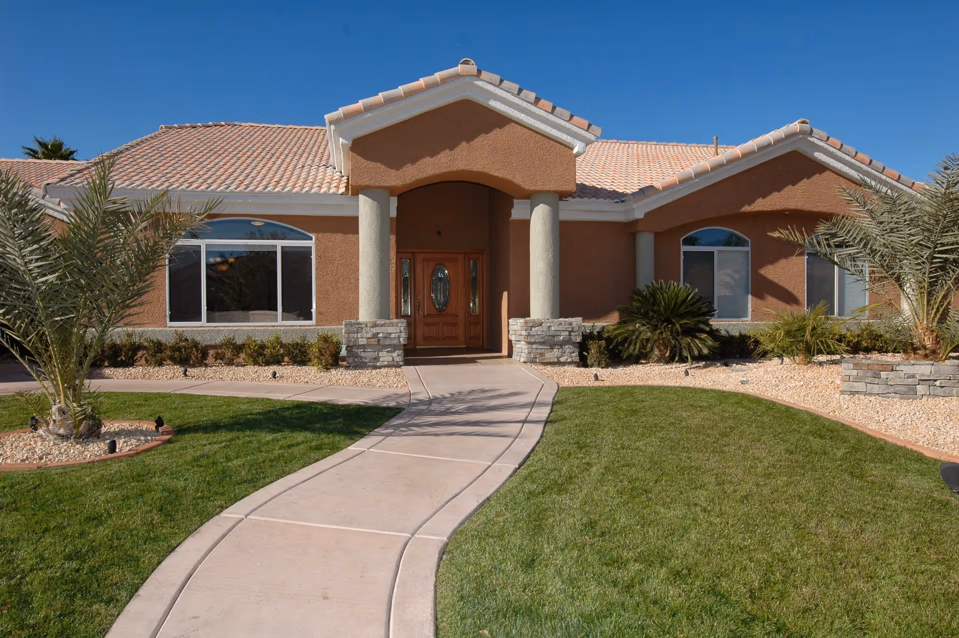 Desert-style senior residence exterior with curved walkway toward a covered central entrance.
