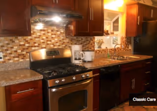 Modern kitchen with dark wood cabinets, mosaic tile backsplash, and stainless steel appliances.