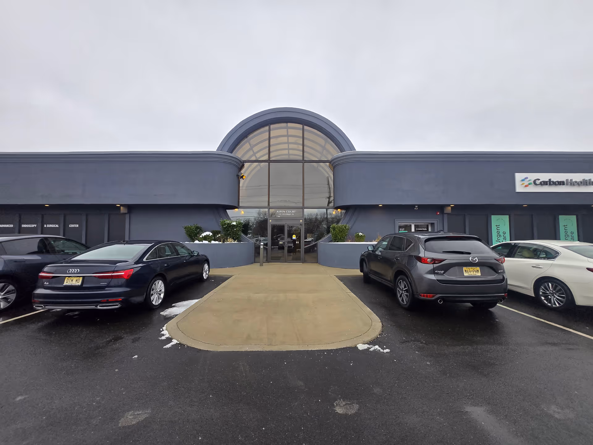 Exterior view of Cyril Senior Care building with arched glass entrance and parked cars