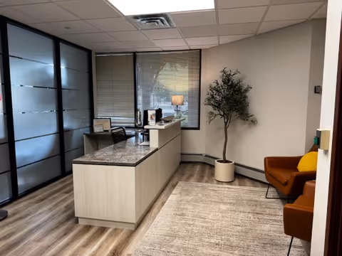 Suncrest Hospice reception area with a curved desk, frosted glass partitions, and seating.