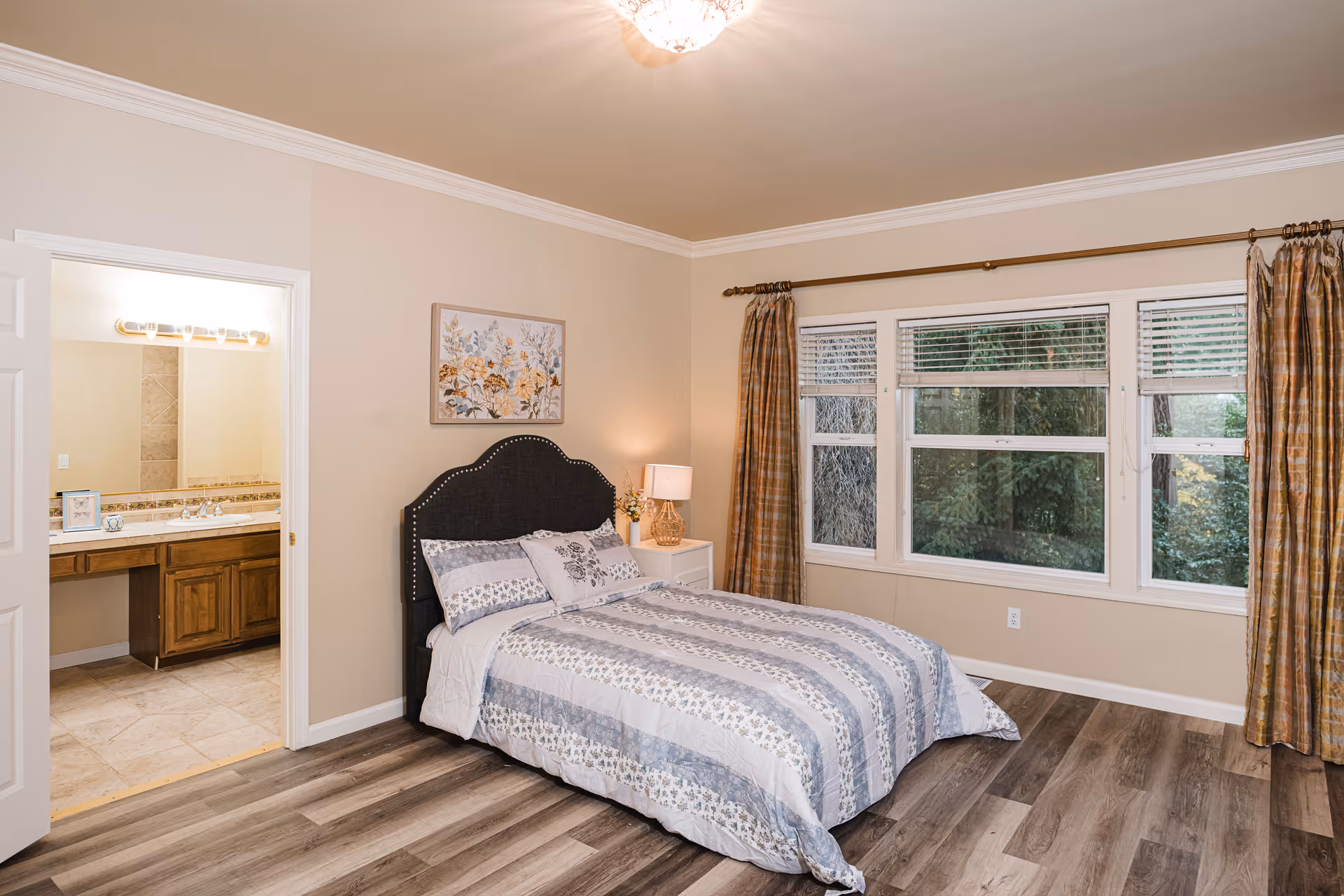 A cozy bedroom with a bed, nightstand, lamp, and doorway to an adjoining bathroom.