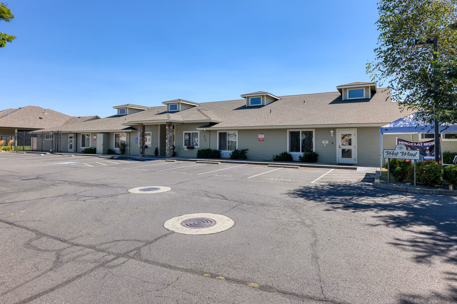 A single-story senior living facility front with parking lot and West Wind sign.