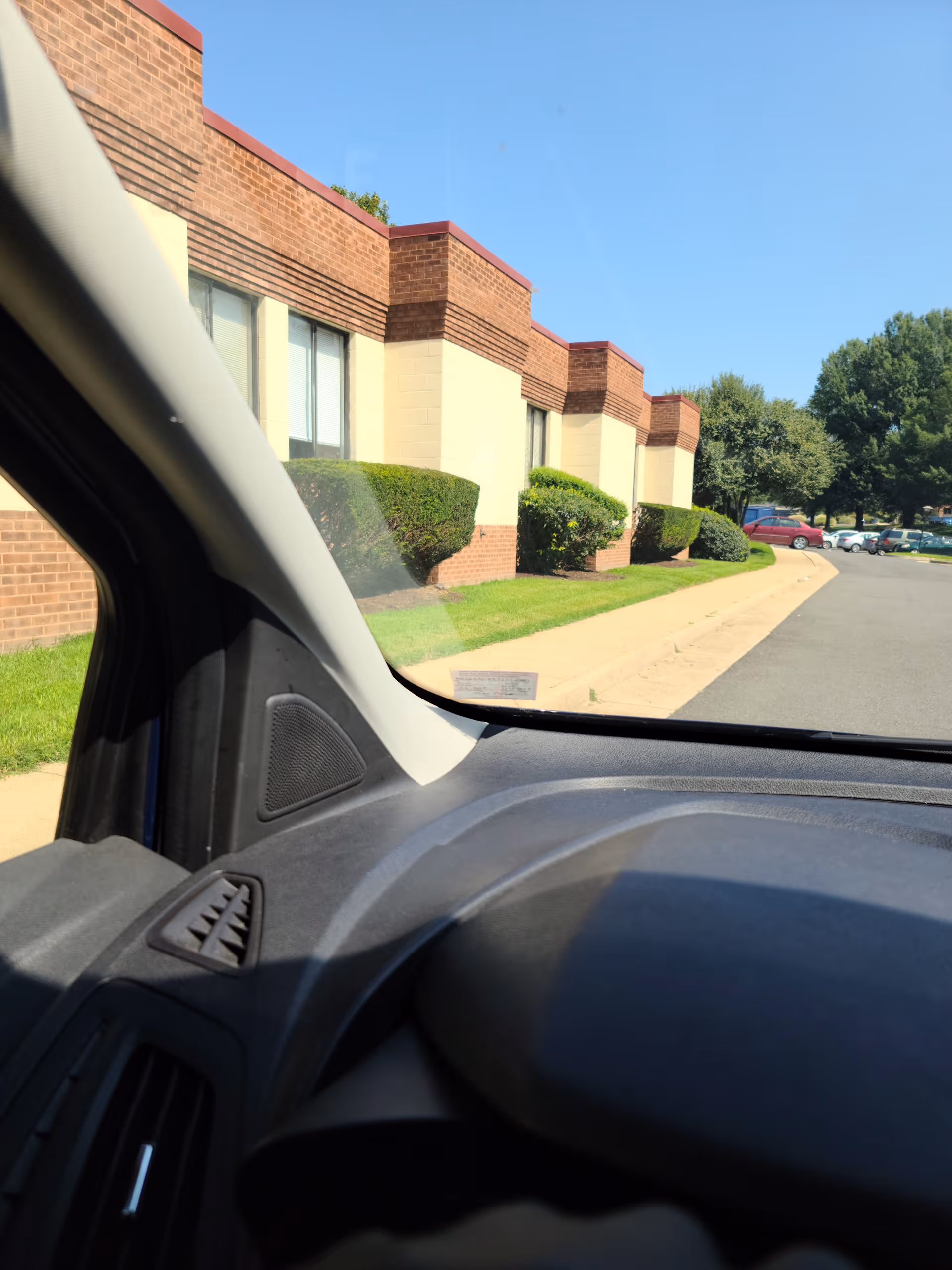View from inside a car of Brookside Rehab & Nursing Center exterior with shrubs.