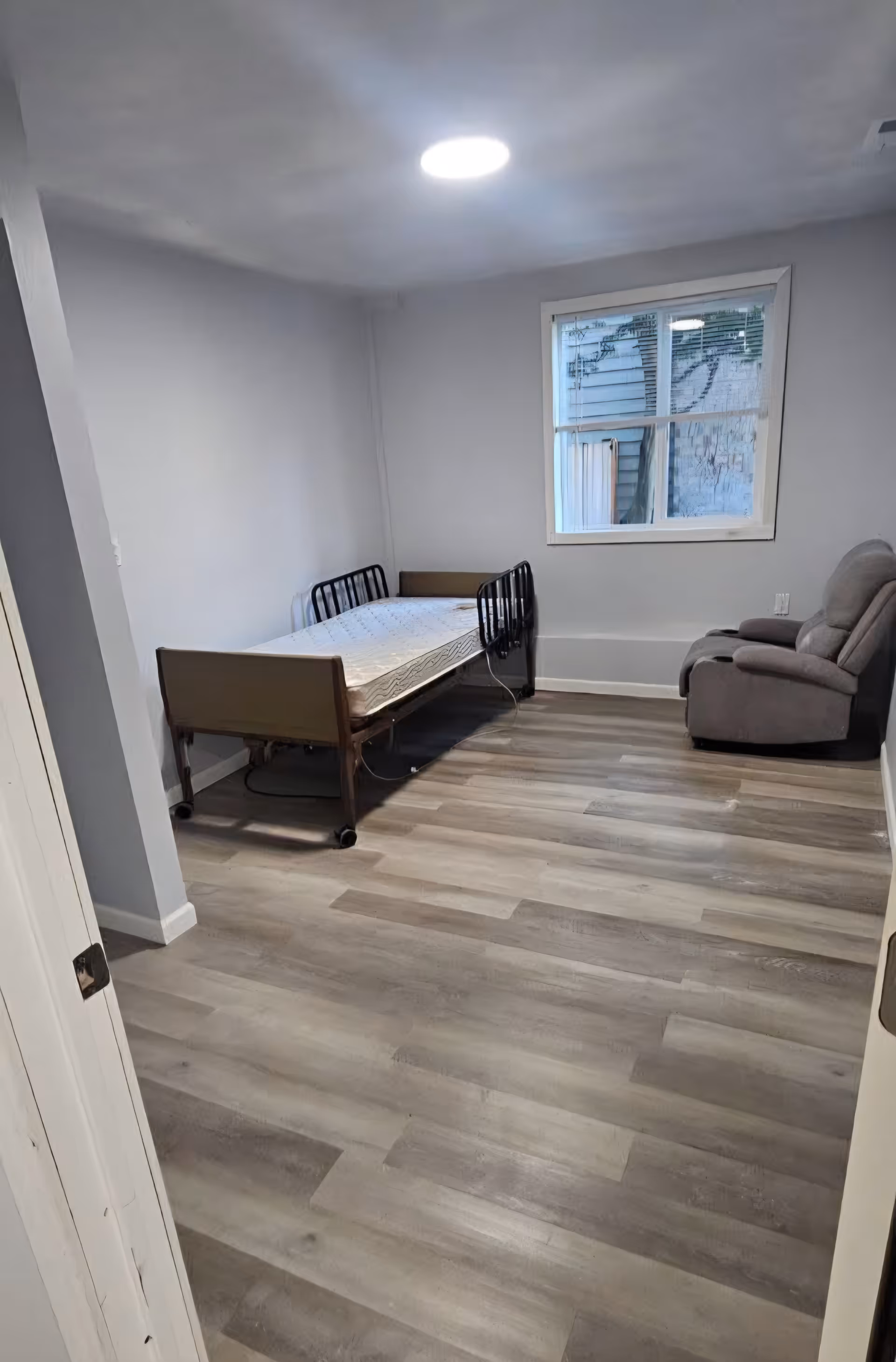 A small bedroom in Evanna Adult Family Home with a hospital-style bed and recliner.
