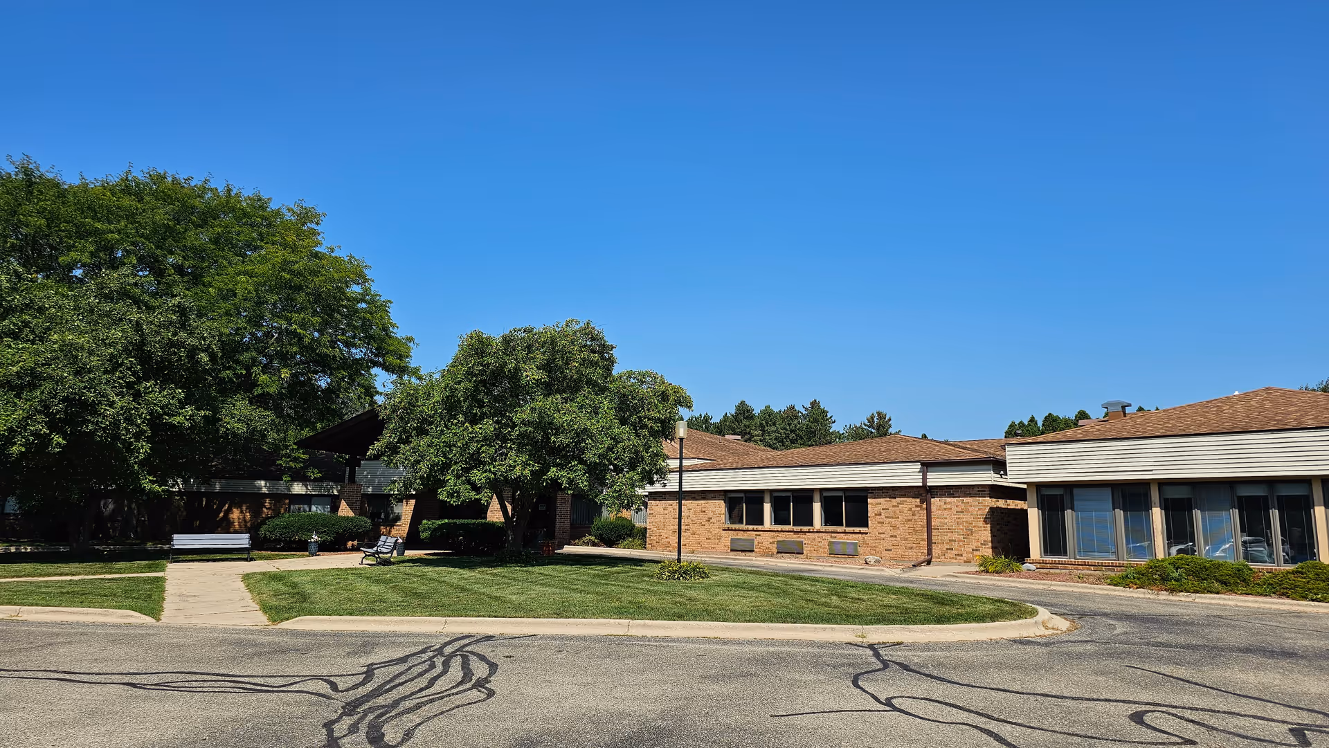 Exterior view of Villa at Middleton Village showing brick building, trees, and sidewalk.