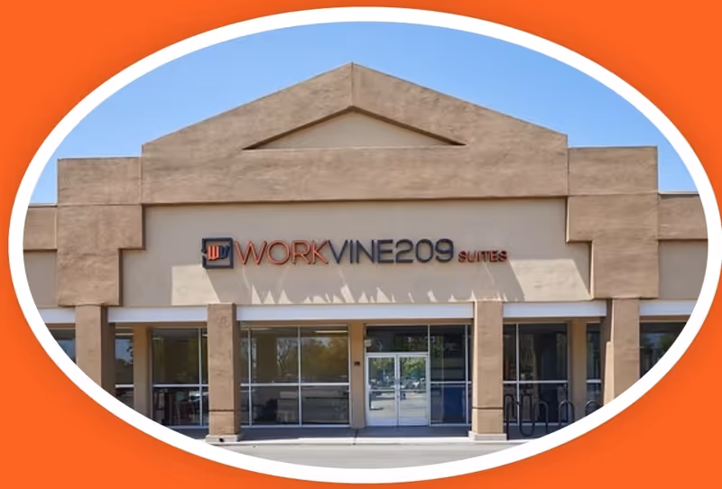 Tan commercial building front with glass doors and signage, blue sky in background