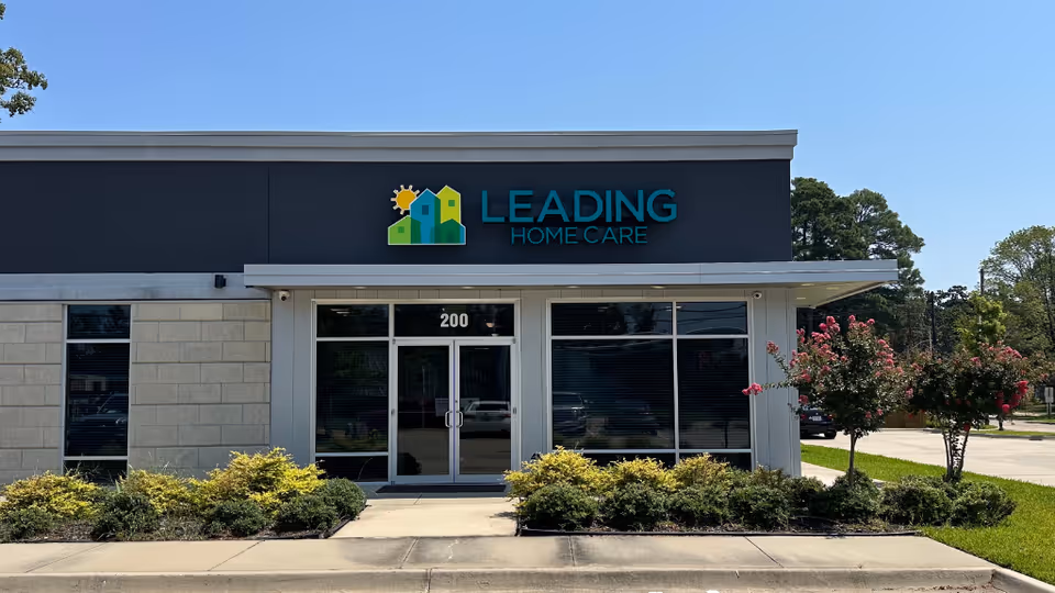Front view of Leading Home Care storefront with glass doors, windows, and landscaped plants