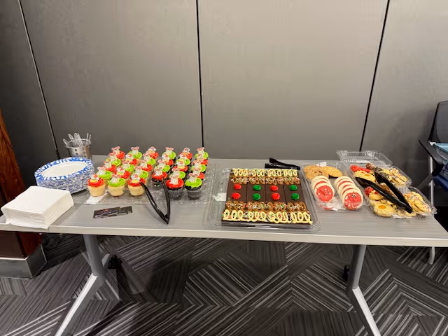 A table with cupcakes, cookies, and plates in a senior care facility.