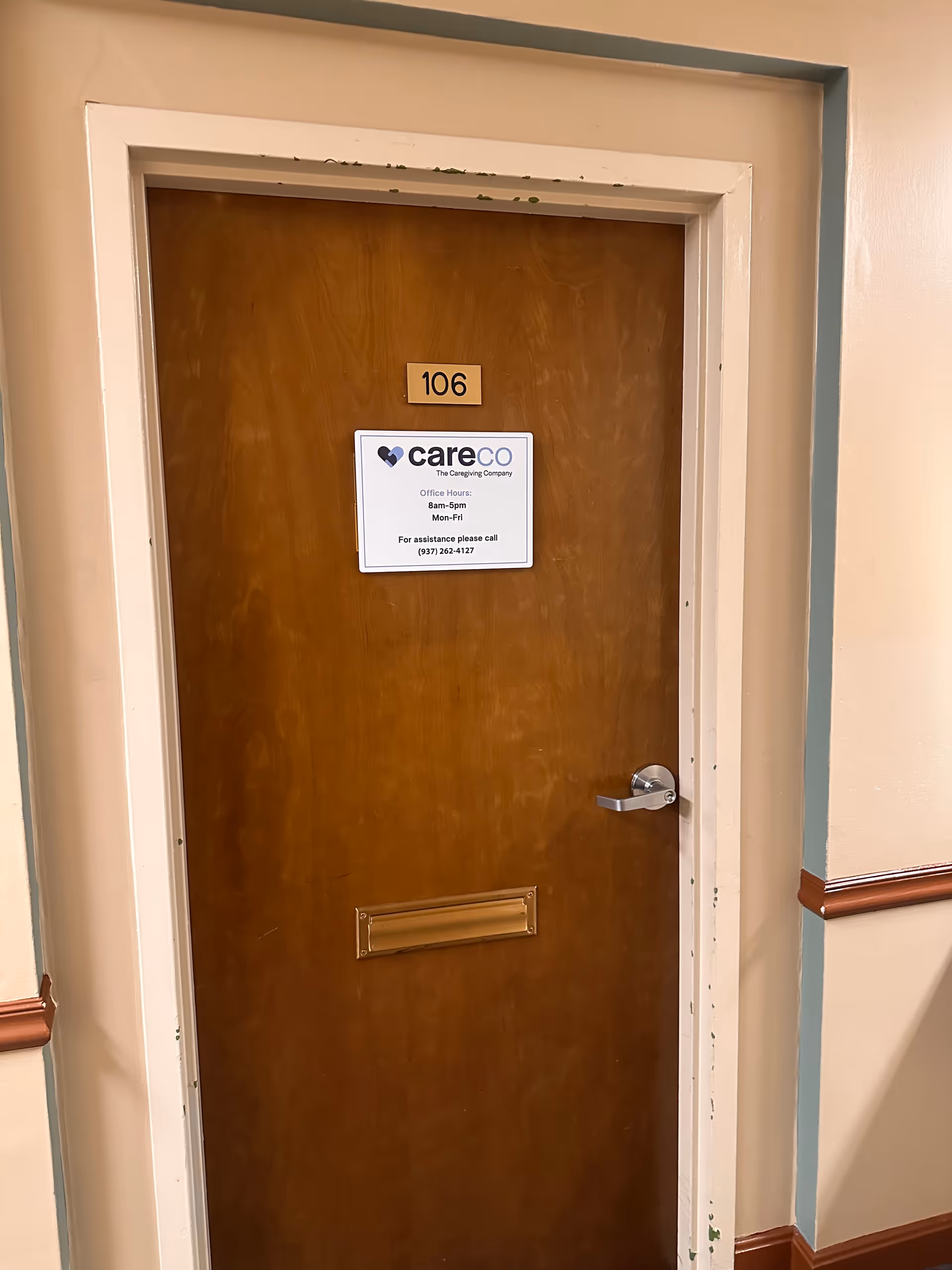 Interior hallway with a wooden door labeled 106 and a CareCo sign posted.