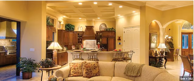 Open living area with a beige sofa, pillows, and a kitchen island visible in back.