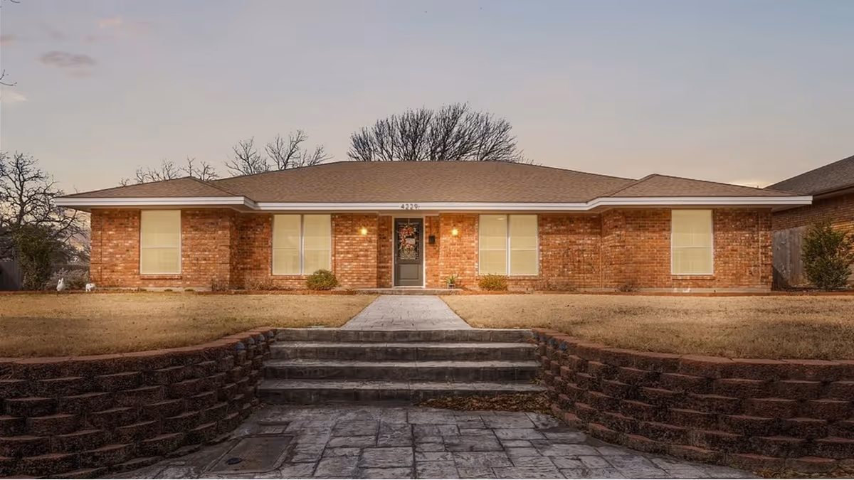 Front view of a single-story brick senior living facility with a central door and steps.