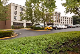 Exterior view of Park Crescent Healthcare and Rehabilitation Center with parked cars and trees.