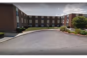 Brick senior living building with curved driveway and landscaped entrance.