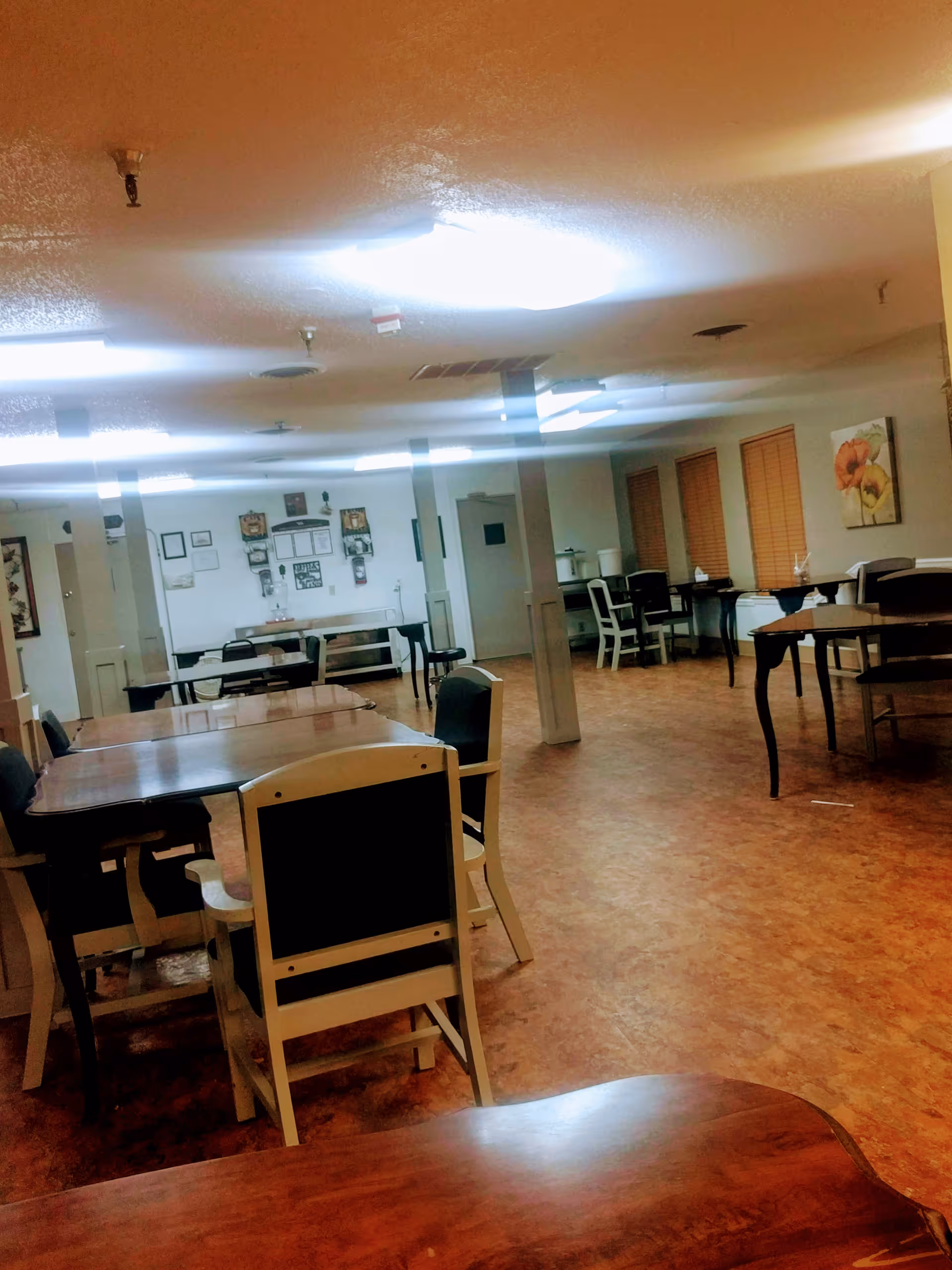 Interior dining room with scattered tables and chairs in a senior living facility.
