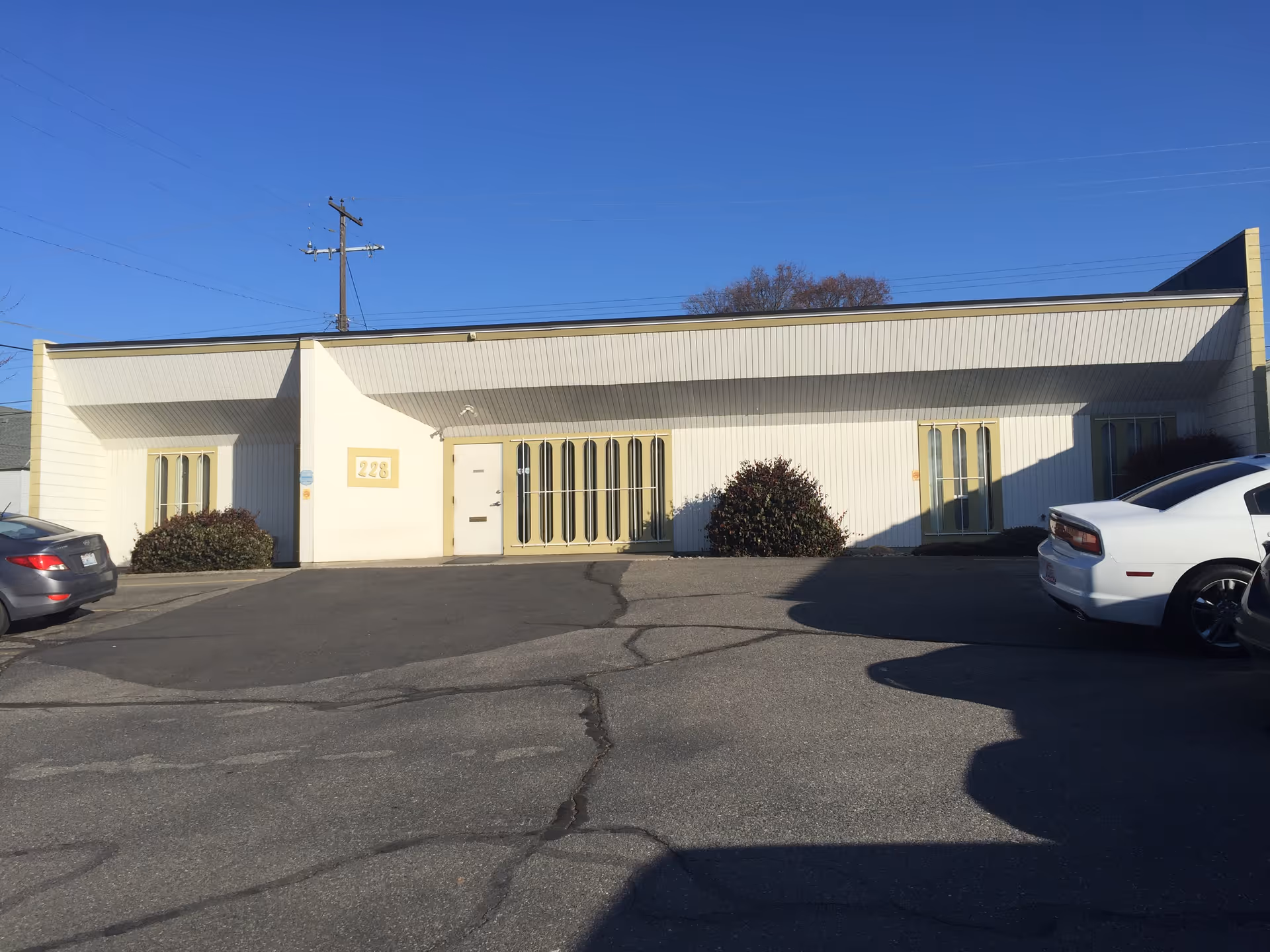 Exterior view of a single-story facility with parked cars in a paved lot.