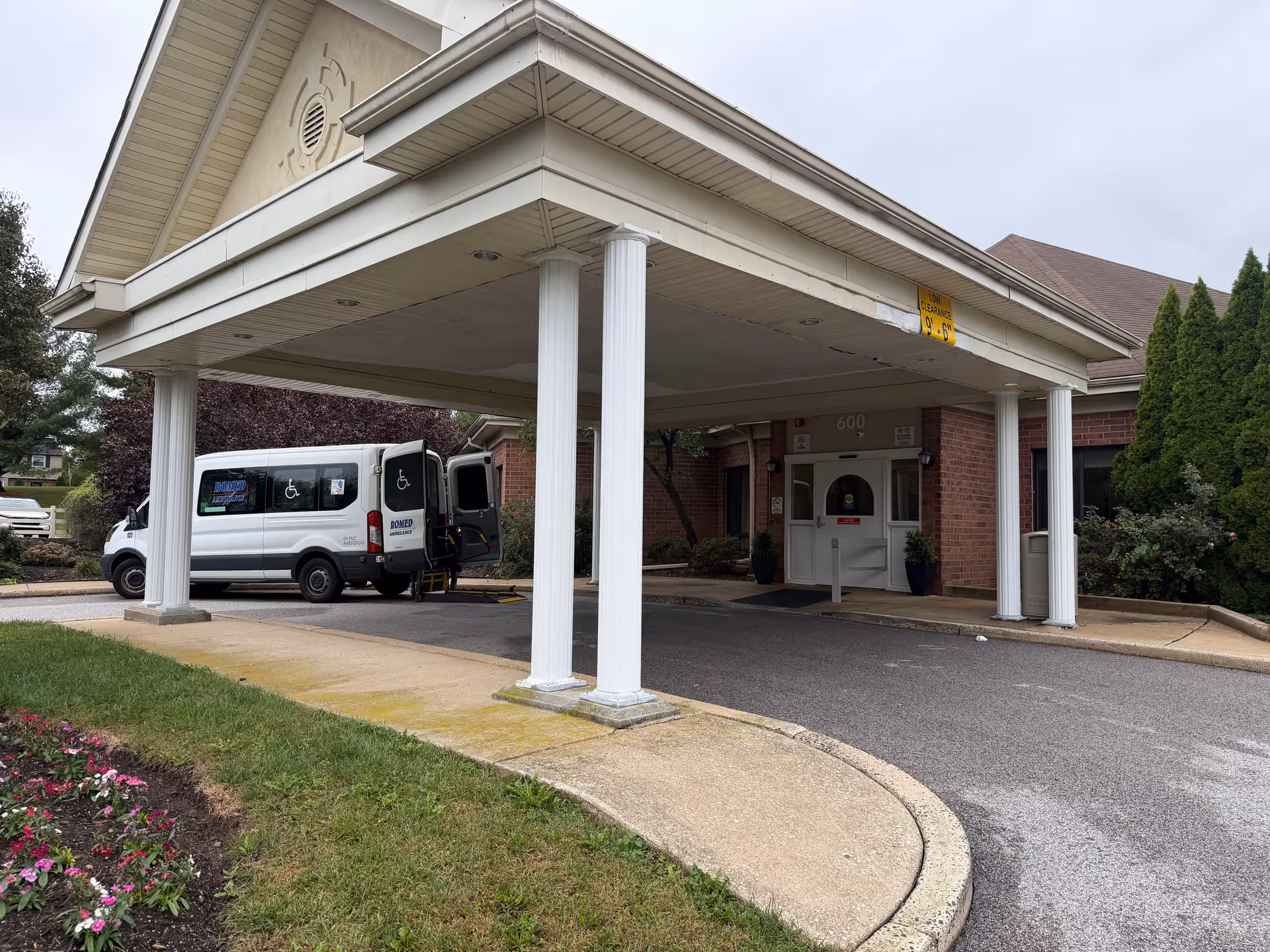 Senior living facility entrance under a covered portico with a wheelchair accessible van.