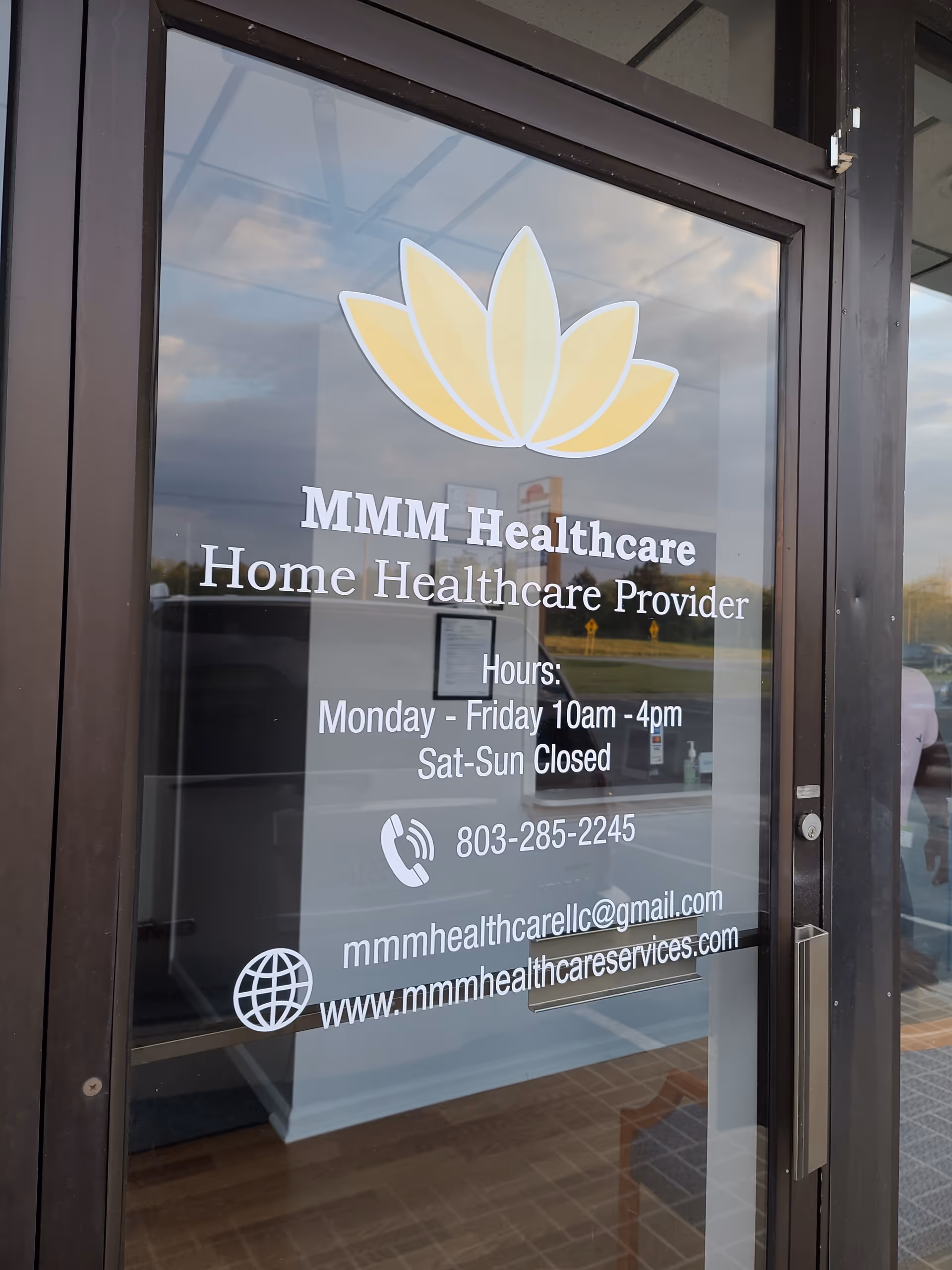 Glass door displays MMM Healthcare logo and contact information for visitors.